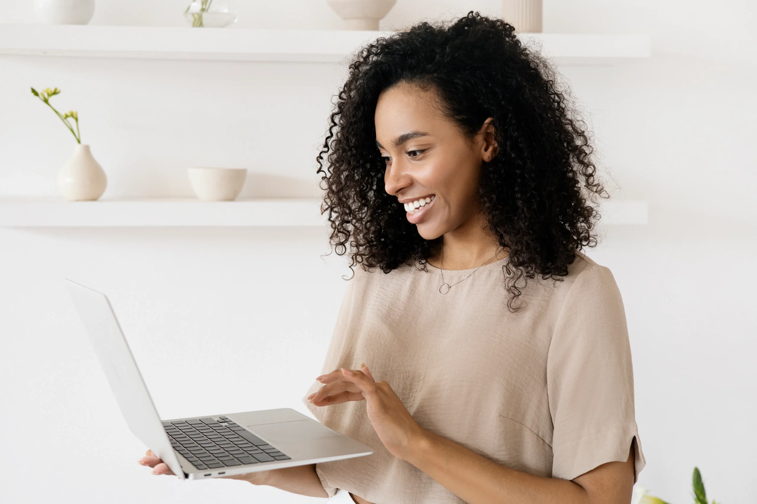 A woman smiles while working on a laptop, possibly taking an ESG online course or sustainable investing course to enhance her skills.