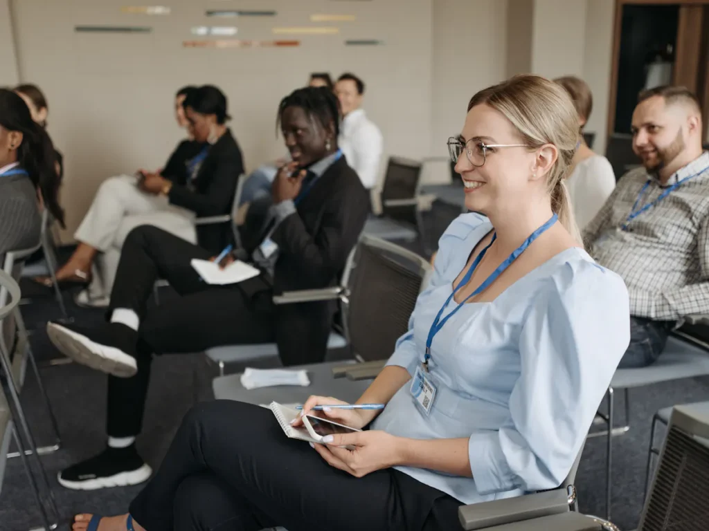 Attendees engaged in ESG training programs, with a woman in the foreground taking notes, indicating a focus on ESG training benefits and career advancement.
