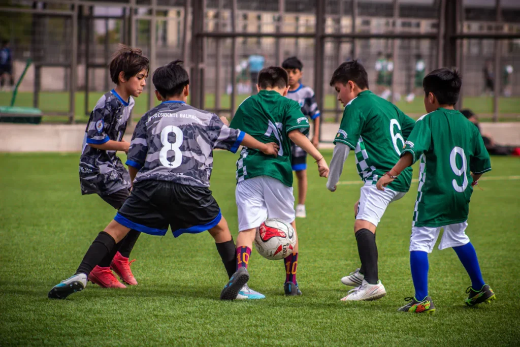 Youth soccer teams play a game on a green field, showcasing teamwork and physical activity.