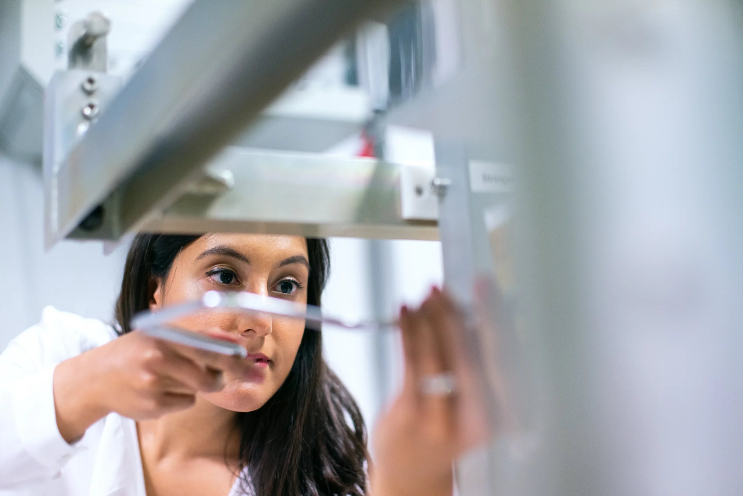 A woman in a lab coat works with scientific equipment, representing the research and development aspect of ESG training and its impact on environmental sustainability.