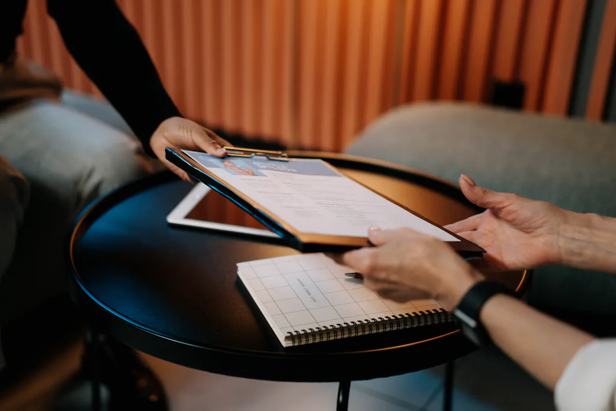 A person handing a resume across a table, possibly for a job related to ESG training or ESG certification courses.