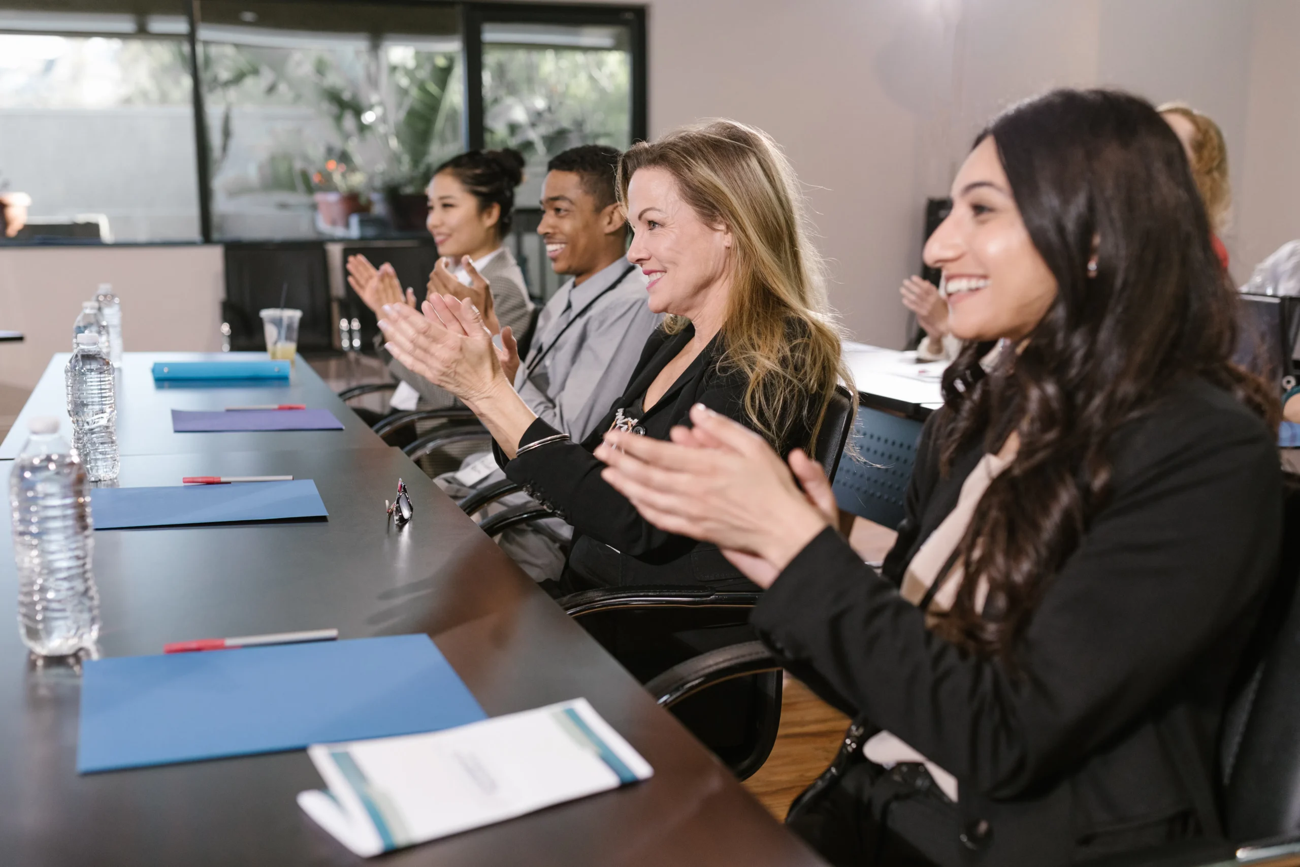 A diverse group of people applauding, suggesting a positive response to a presentation or training, potentially related to ESG training, ESG courses, and ESG certification, indicating the value of such programs in professional settings.